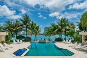 a custom luxury inground pool with palm trees and beautiful lake background