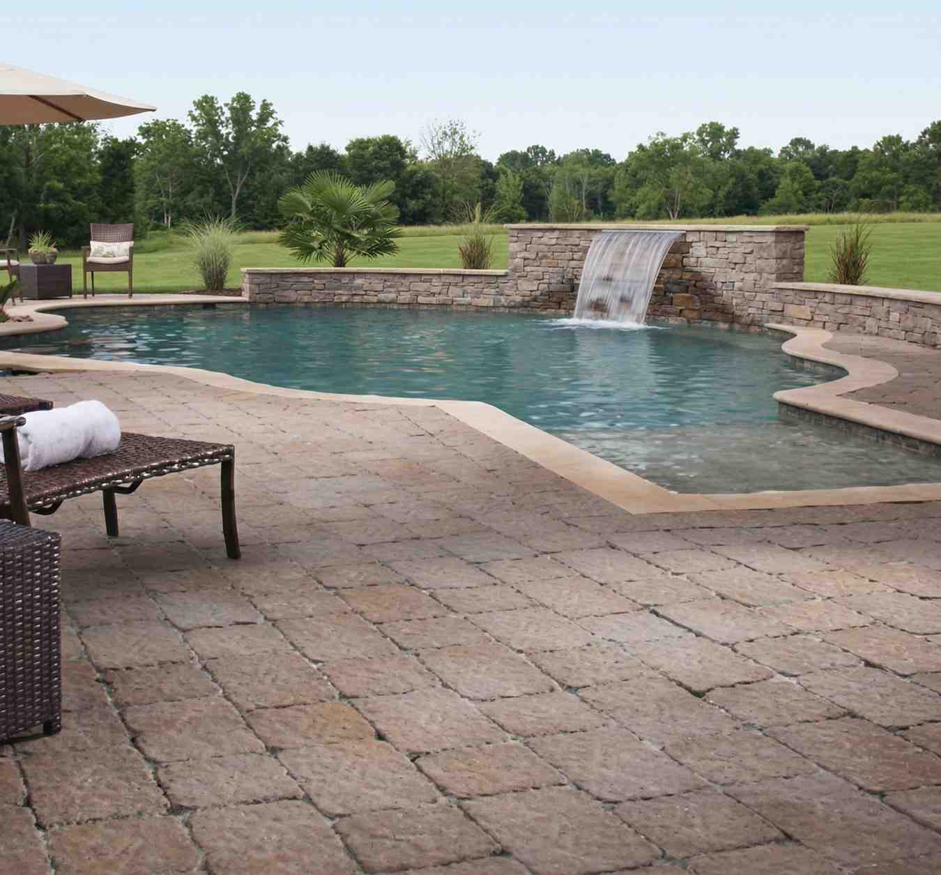 natural stone used for pool decking aroud a small pool with water feature