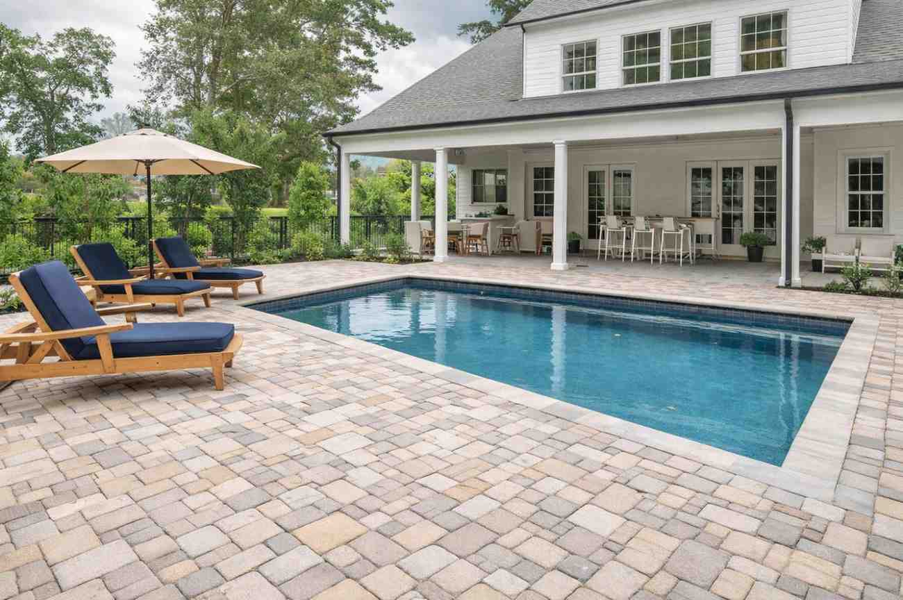 beautiful pool decking around a small rectangular pool in backyard